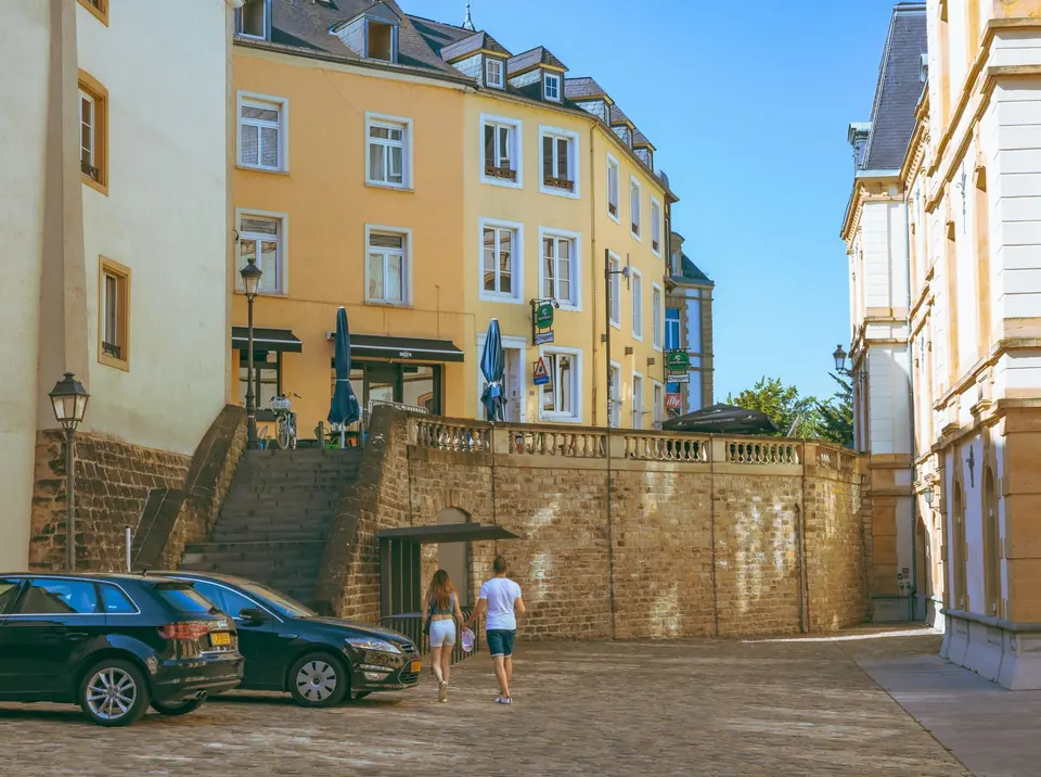 Ein Paar spaziert entlang einer malerischen Straße in der Stadt Luxemburg und zeigt historisches Architektur und urbanen Charme.